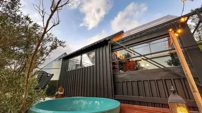 a tiny house with a hot tub in the backyard at Riverside Glass Cabin Franschhoek in Franschhoek