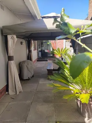 a patio with a green umbrella and a plant at Urban Oasis Cape Town in Cape Town