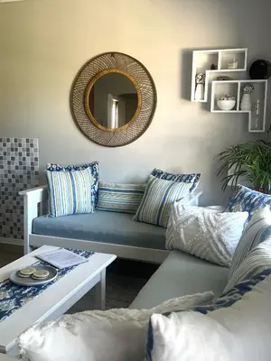 a living room with a blue couch and a mirror at Serenity self-catering 2-bed unit in Hermanus