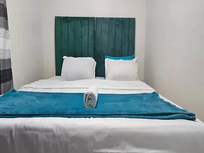 a large bed with a green headboard and white pillows at Goshen Lodge Spencer in Cape Town
