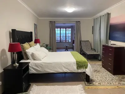 a bedroom with a bed and a dresser and a television at Lakeview Cottage: Rural Retreat in Pampoenkraal