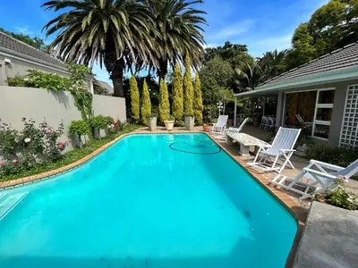a swimming pool with chairs and a house at Somerset West All Stay 2 in Somerset West