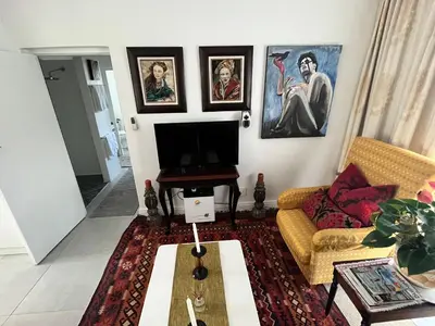 a living room with a couch and paintings on the wall at Somerset West All Stay 2 in Somerset West