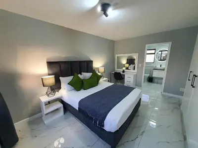 a bedroom with a large bed with green pillows at Knightsbridge Superior Apartments in Cape Town