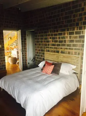 a bedroom with a white bed with a brick wall at Secure, luxurious with lovely views in Pringle Bay