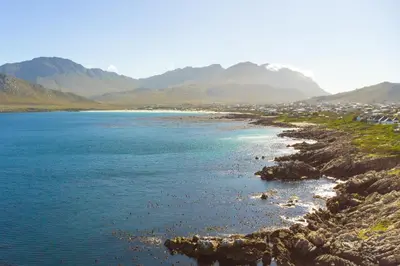 a body of water with mountains in the background at Secure, luxurious with lovely views in Pringle Bay