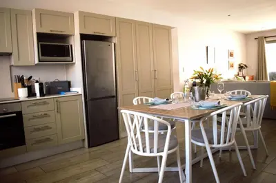 a kitchen with a table with chairs and a refrigerator at Spacious, Modern & Convenient in Franschhoek