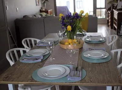 a dining room table with plates and a vase of flowers at Spacious, Modern & Convenient in Franschhoek