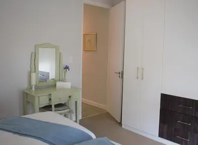 a bedroom with a bed and a desk with a mirror at Spacious, Modern & Convenient in Franschhoek