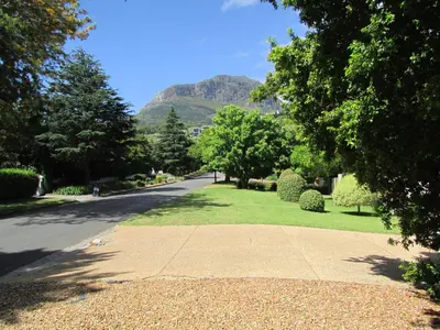 a street with trees and a mountain in the background at Lovely Concordia, rental unit with free parking in Cape Town