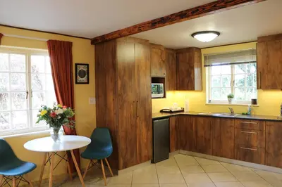 a kitchen with wooden cabinets and a table and chairs at Lovely Concordia, rental unit with free parking in Cape Town