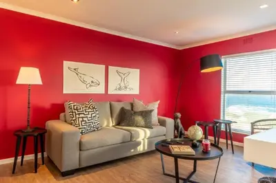 a living room with a couch and a red wall at Whale Rock 25 in Hermanus