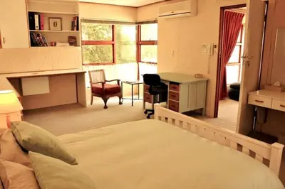 a bedroom with a bed and a desk in a room at The View Upstairs - A spacious apartment with a view in Durbanville