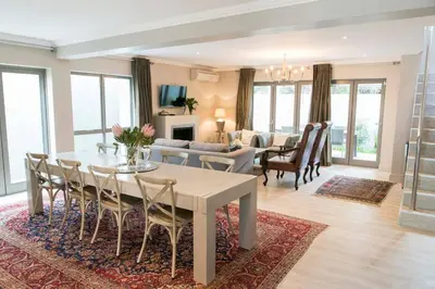 a dining room and living room with a table and chairs at 13 La Gratitude Luxury Apartment-with backup power for loadshedding in Stellenbosch