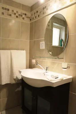 a bathroom with a sink and a mirror and towels at Lovely Kaapgracht, rental unit with free parking in Cape Town