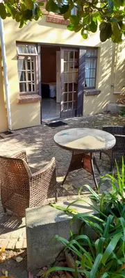 a patio with a table and chairs in front of a building at Lovely Kaapgracht, rental unit with free parking in Cape Town