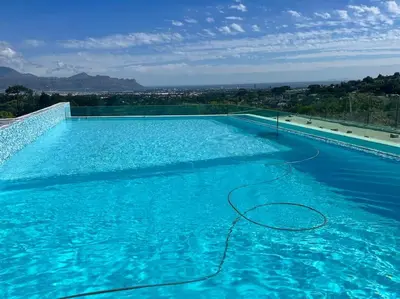 a large blue swimming pool with a hose at Amazing! 7 bedroom villa with rooftop pool & views in Cape Town