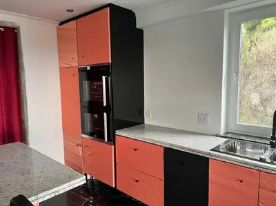 a kitchen with red and black cabinets and a sink at Amazing! 7 bedroom villa with rooftop pool & views in Cape Town