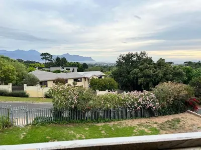 a fence in front of a house with flowers at Amazing! 7 bedroom villa with rooftop pool & views in Cape Town