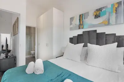 a white bedroom with a large bed with white pillows at Atlantic Port 9 by Host Agents in Bloubergstrand