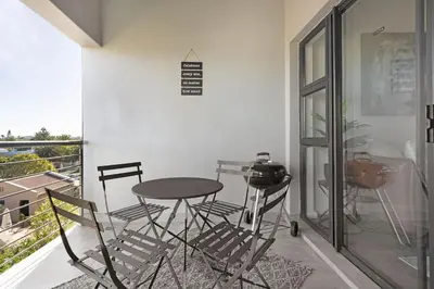 a table and chairs in a room with a balcony at Atlantic Port 9 by Host Agents in Bloubergstrand