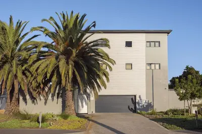 a palm tree in front of a building with a garage at Atlantic Port 9 by Host Agents in Bloubergstrand