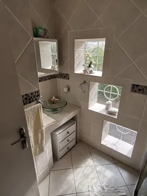 a small bathroom with a sink and two windows at Somerset west Mountain road cottage in Cape Town