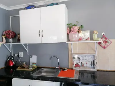 a kitchen counter with white cabinets and a sink at Somerset west Mountain road cottage in Cape Town
