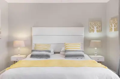 a bedroom with a large white bed with two lamps at Witsand 804 in Bloubergstrand