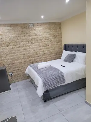 a bedroom with a large bed and a brick wall at MIRAJO Guest House in Cape Town