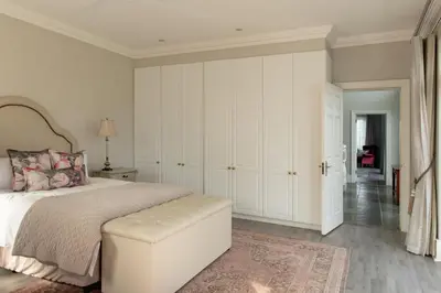 a white bedroom with a bed and a ottoman at Faraway Estate in Villiersdorp