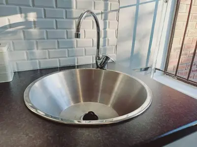 a kitchen sink with a cat sitting inside of it at Charm Nest - Uncapped Wi-fi & Self Check-in in Cape Town