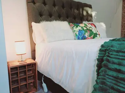 a bed with a white blanket and a lamp on a night stand at Charm Nest - Uncapped Wi-fi & Self Check-in in Cape Town
