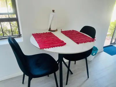 a white table with two black chairs and red knitted blankets at Charm Nest - Uncapped Wi-fi & Self Check-in in Cape Town