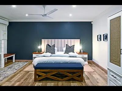 a bedroom with a large bed with a blue wall at Ashbourne Boutique Guest House in Franschhoek