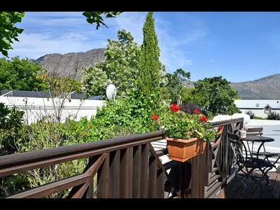 a balcony with a table and flowers on a fence at Ashbourne Boutique Guest House in Franschhoek