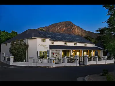 a white building with a mountain in the background at Ashbourne Boutique Guest House in Franschhoek