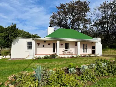a white house with a green roof at Cottage at Kanu Wines in Cape Town