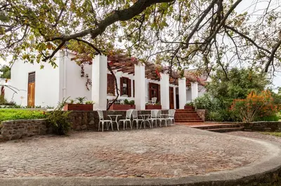 a patio in front of a white house with chairs at Ayama Wine Farm - Manor House in Wellington