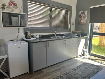 a kitchen with white cabinets and a sink and a window at The Charming Place in Cape Town