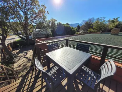 a wooden table and chairs on a deck at Elegantie Apartment Protea 5 Lovell Avenue in Stellenbosch