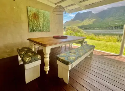 a wooden table and bench on a deck with a view at Tranquility in Hermanus