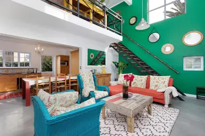 a living room with blue and red furniture and a green wall at Sunset Yellow Cottage in Cape Town