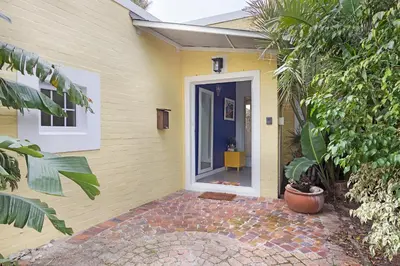 a yellow house with a door and a courtyard at Sunset Yellow Cottage in Cape Town