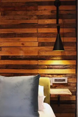 a bedroom with a wooden wall with a bed and a lamp at Well Appointed Apartment by ARPA Hospitalities in Stellenbosch