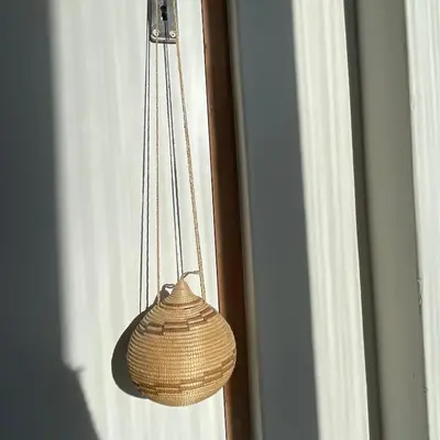 a wicker basket hanging from a door with a window at Suikerbos in Pringle in Pringle Bay