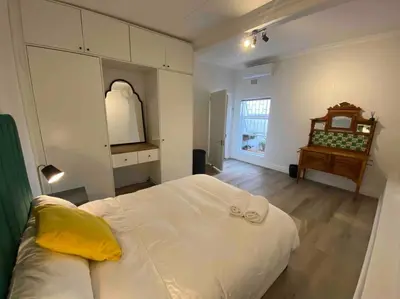 a bedroom with a large white bed and a table at Auret Street Garden Cottage in Paarl