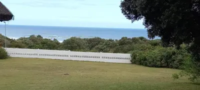a white fence with the ocean in the background at Grotto Cottage in Hermanus