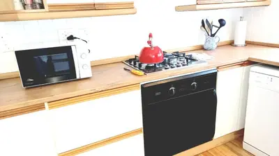 a kitchen with a black dishwasher and a microwave at Grotto Cottage in Hermanus