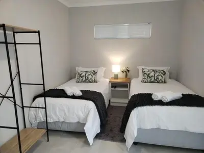 a bedroom with two beds and a night stand with a lamp at Harmonie Self Catering in Wolseley